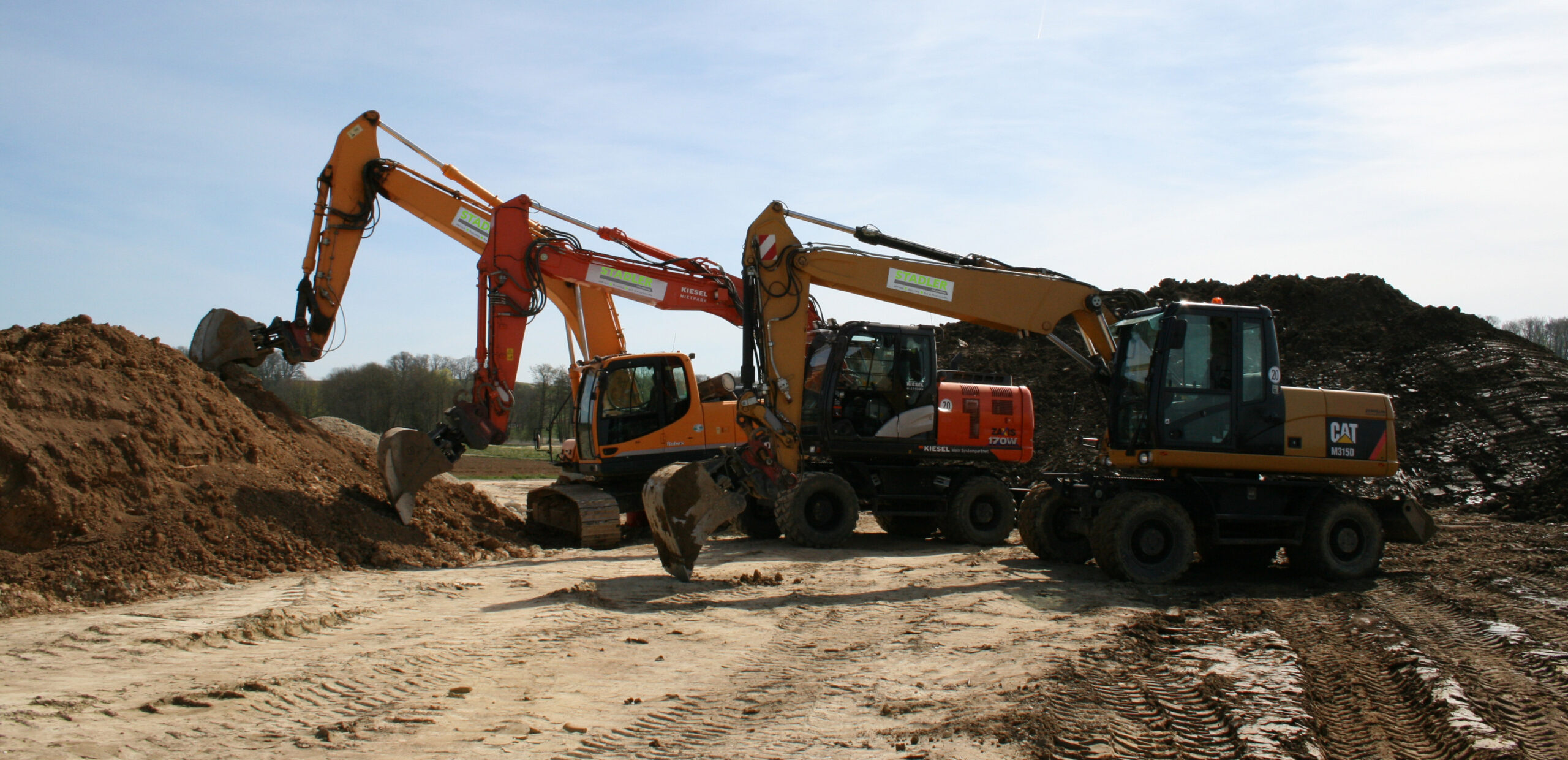 Drei Bagger der Marken Hitachi und CAT bei Erdarbeiten auf einer Baustelle von Fa. Stadler Thalmassing